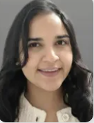 A woman with black hair in a white blouse is smiling.