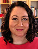 Headshot of April Craft, a woman with short dark curly hair who wears a red shirt smiles for the camera.