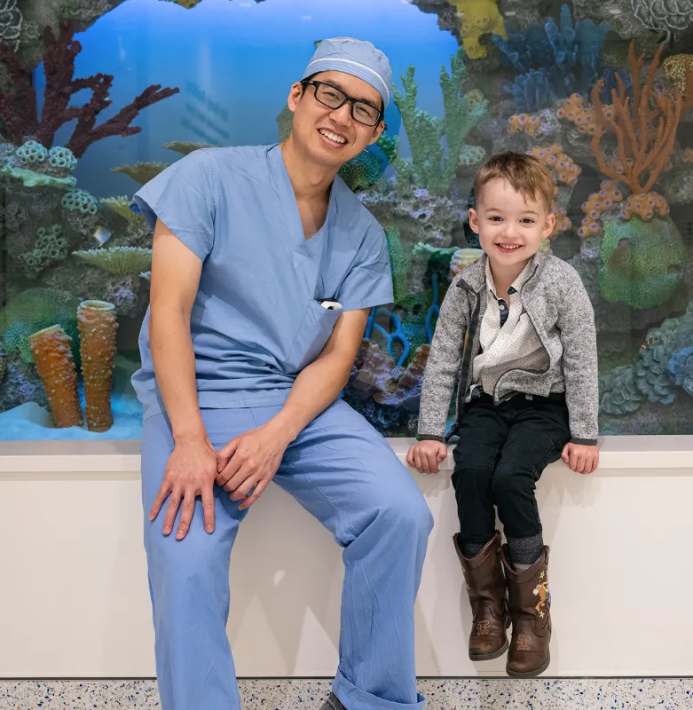 physician and child sitting on a bench with a background aquarium