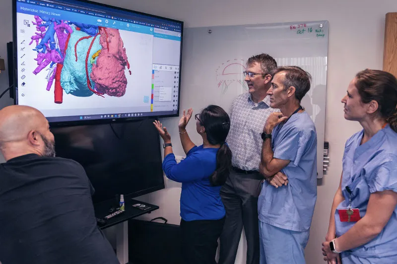 Three men and four women looking at a 3D model of a heart on a screen