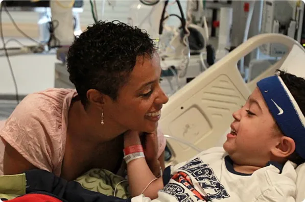Woman talking to child lying in hospital bed