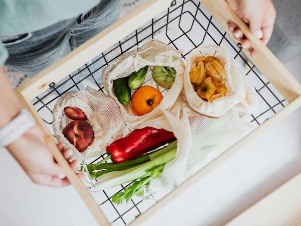 A person holding a basket full of fruits and vegetables 