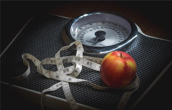 An apple and measuring tape on a scale