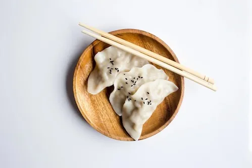 Plate of three dumplings with chopsticks 
