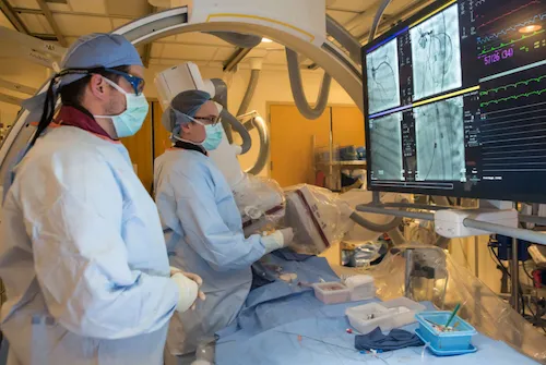 Two doctors looking at a screen while performing a mitochondrial transplant