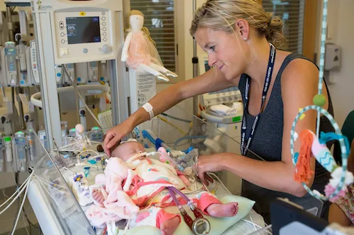 A woman looking over a baby in the NICU