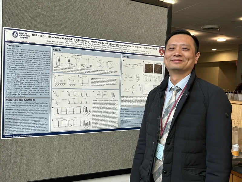 A man stands next to a poster of his scientific presentation.
