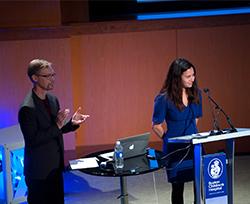 A man and a woman speak up at a podium. 