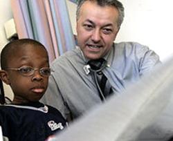 A man and a boy look at a newspaper together. 