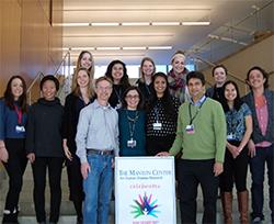 A group of people who work for the manon center gather around a sign. 