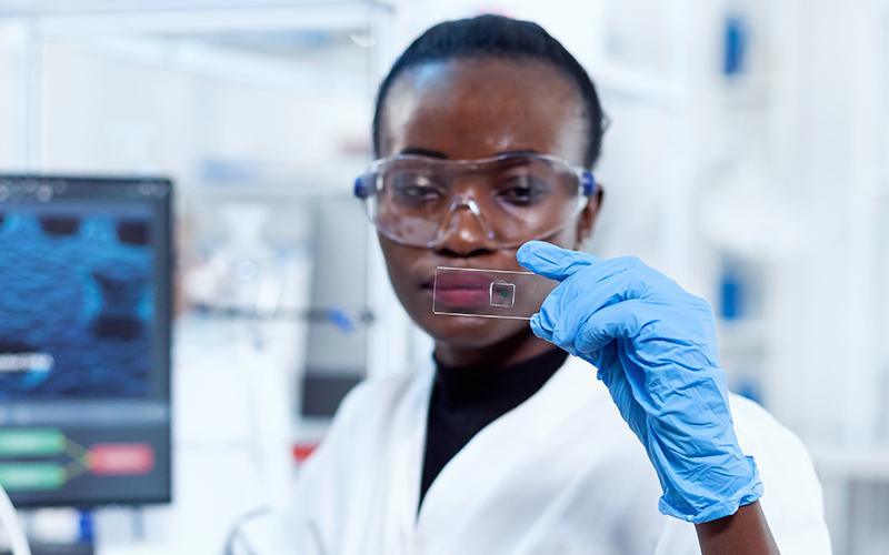 A woman look's at a microscope slide.