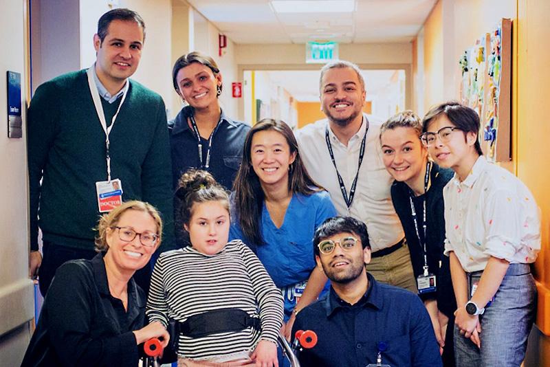 Five women, three men and a young girl standing inside a hospital hallway