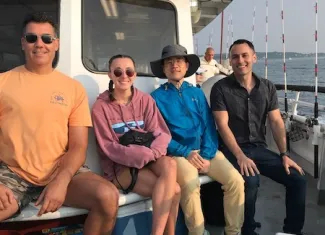three men and one woman on a fishing boat
