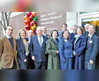 A group of people in dress clothes standing in front of a brick building.
