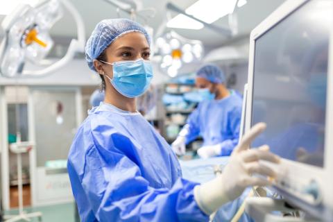 Clinician wearing mask looks at data on monitor