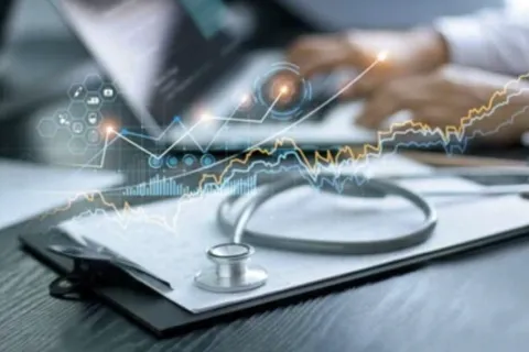 stethoscope on top of clipboard and person typing on a laptop