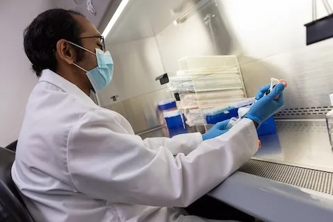 Male doctor wearing a face mask holding a pipet