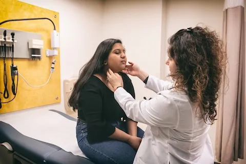 A woman doctor checking a girl's throat