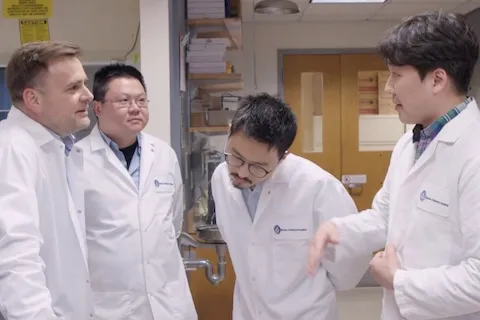 Four men in lab coats talking