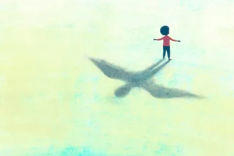 boy standing with arms out and a shadow of the boy with wings