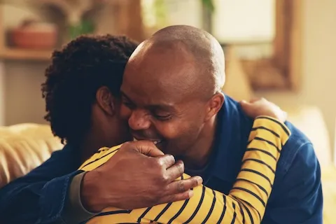 A dad and teenage boy hugging